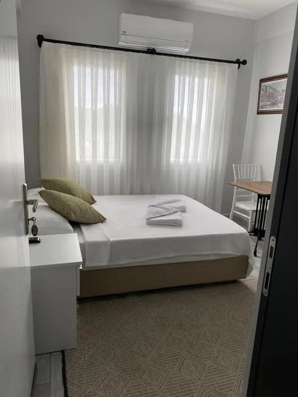 Une chambre lumineuse avec un lit recouvert d'une courtepointe et d'oreillers.
