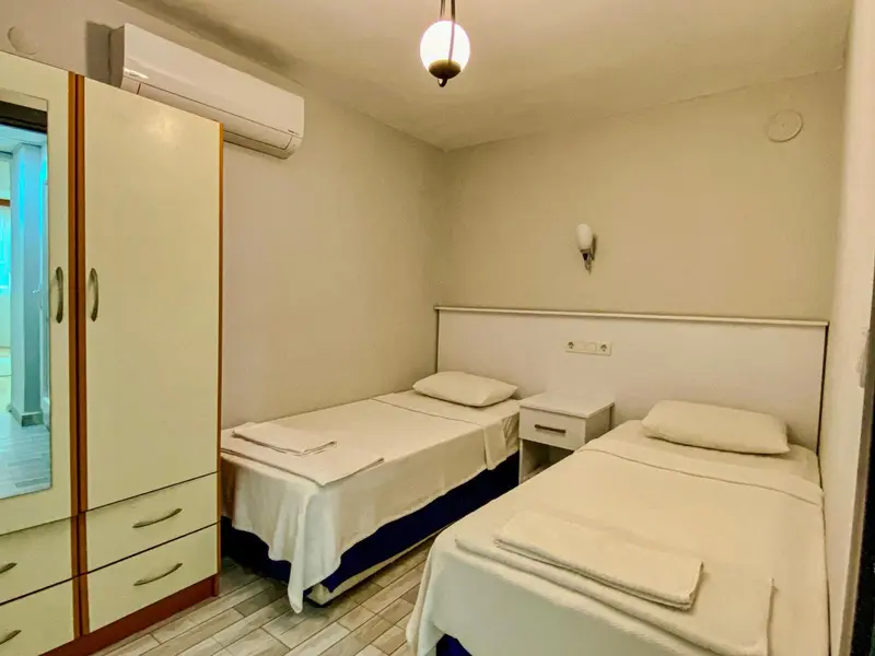 Une chambre avec deux lits simples et une armoire.