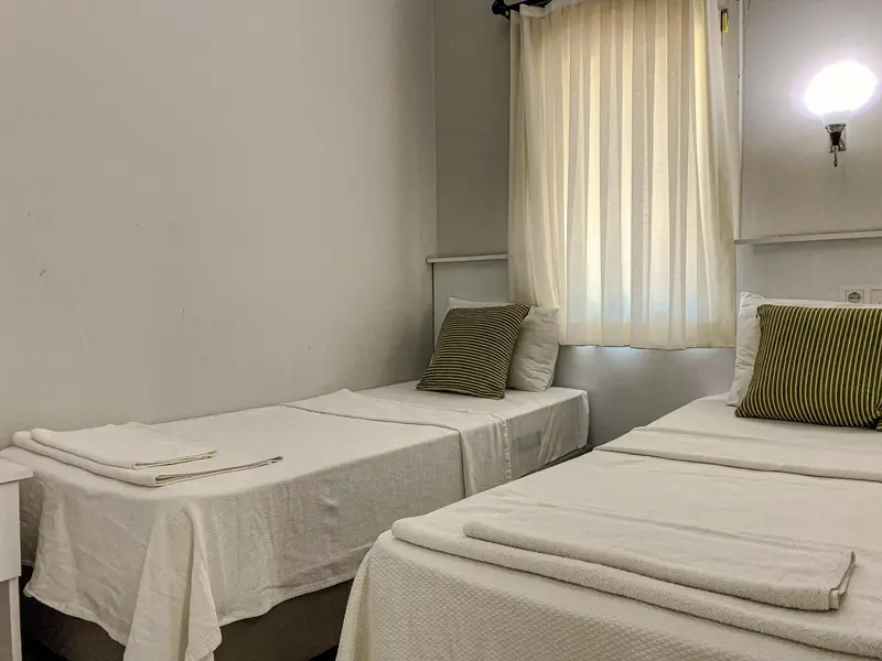 Une chambre avec deux lits simples et une fenêtre.