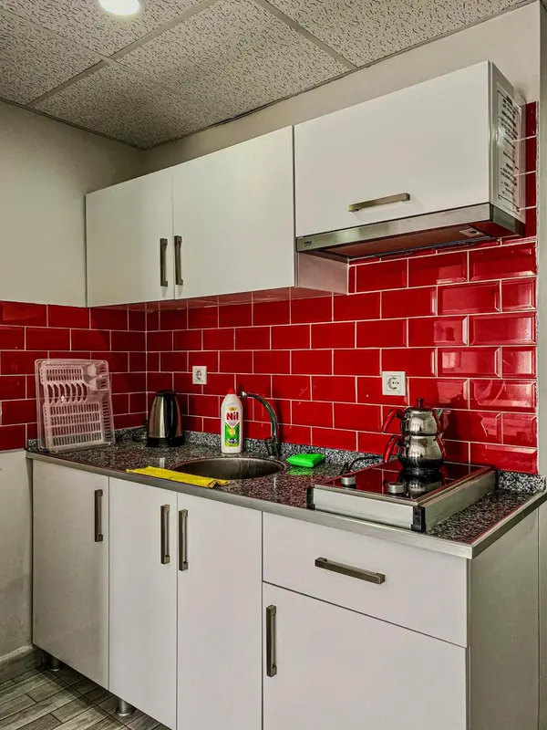 Une cuisine moderne avec des armoires blanches et un carrelage rouge.