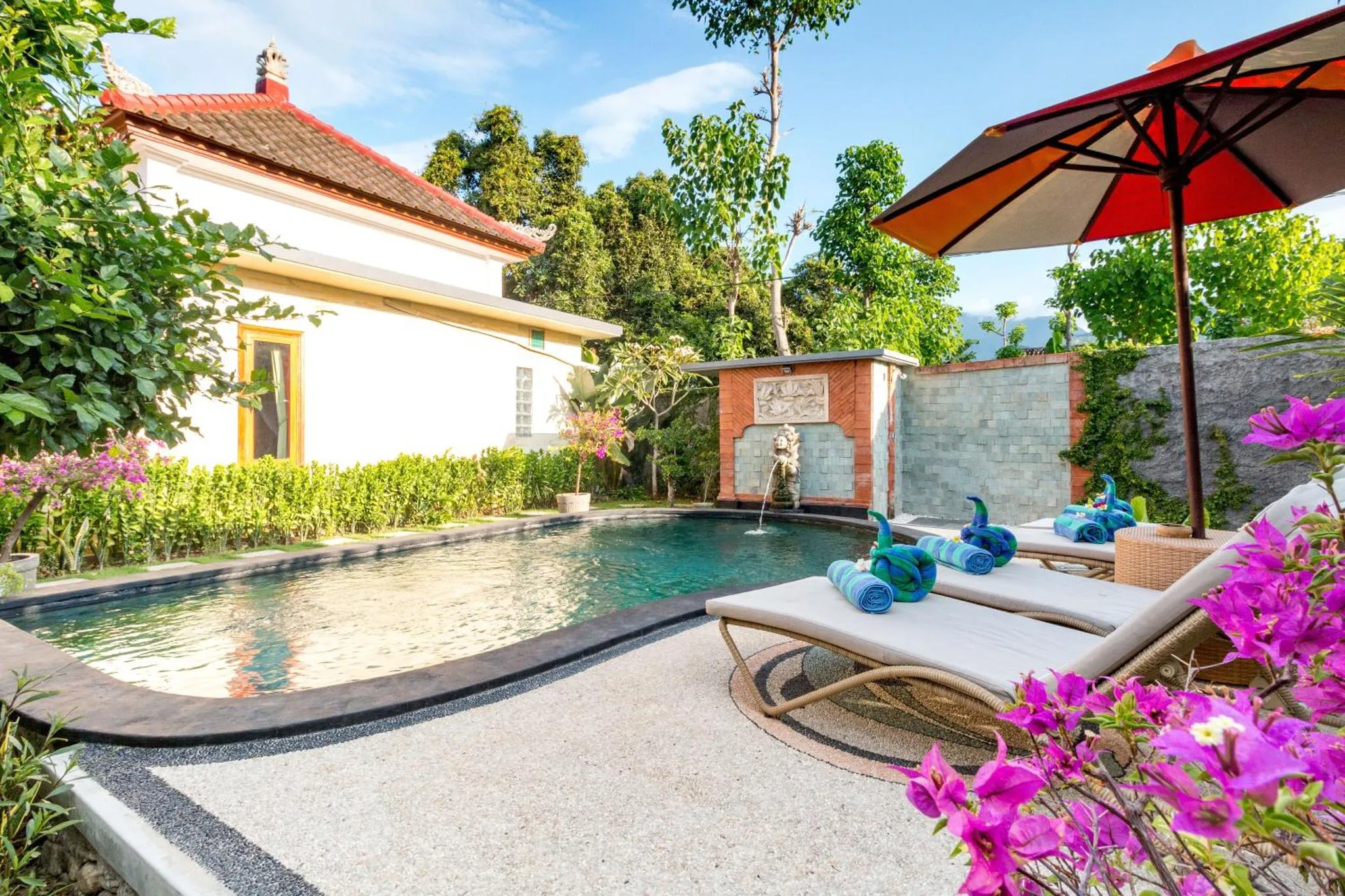 Transats et petite piscine dans un jardin tropical.