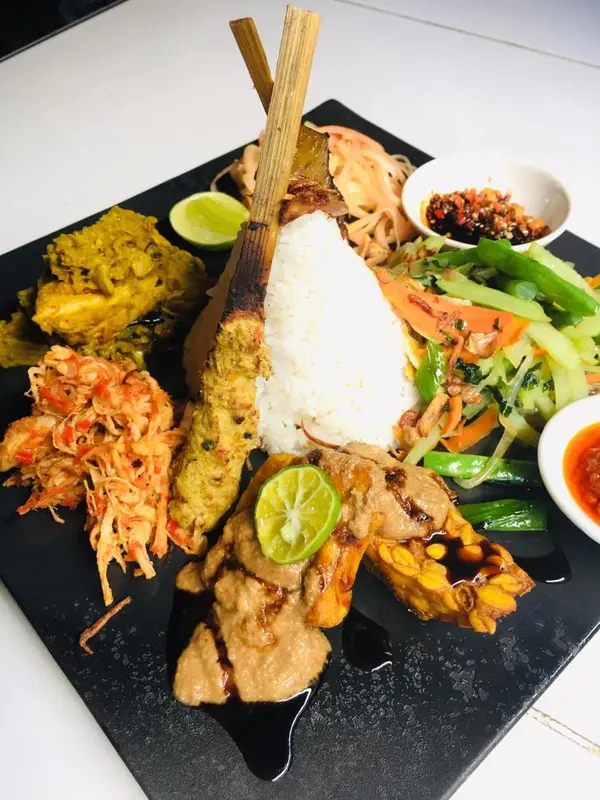 Assiette généreuse de spécialités locales avec riz, brochettes et accompagnements.