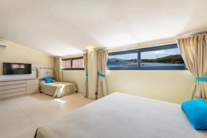 Chambre lumineuse avec vue sur la mer par une grande fenêtre.