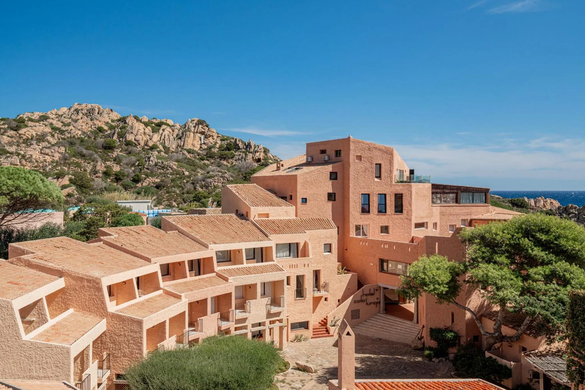 Bâtiment de couleur ocre avec terrasses et vue sur la mer.