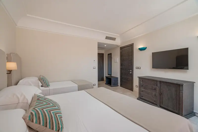 Chambre lumineuse avec deux lits simples et une commode en bois.