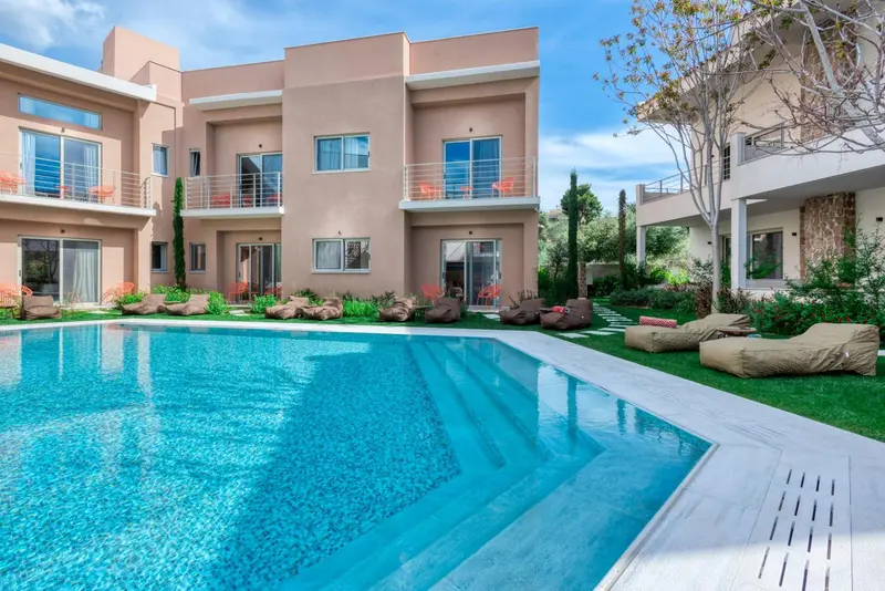 Piscine rectangulaire turquoise bordée d'une terrasse ensoleillée avec des transats.