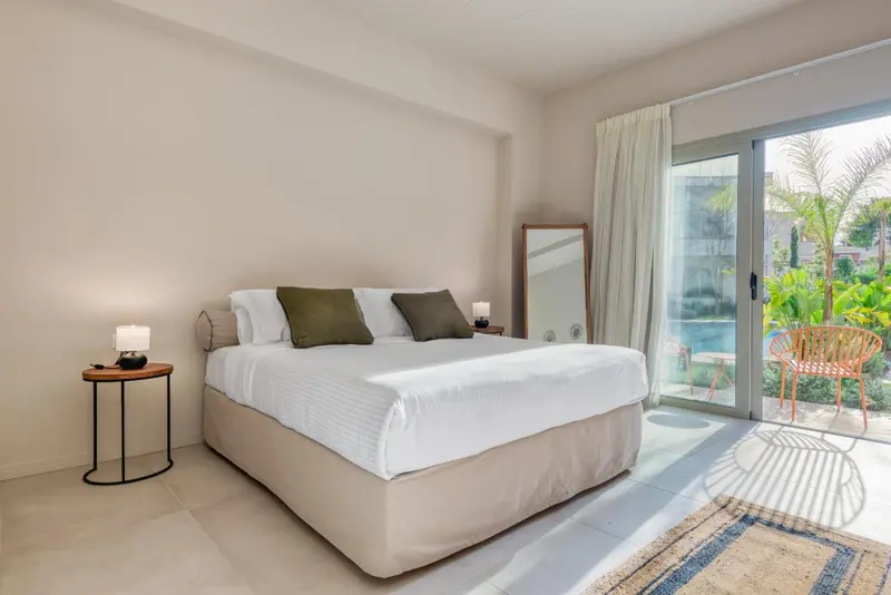 Une chambre lumineuse avec un grand lit et un accès à une terrasse.