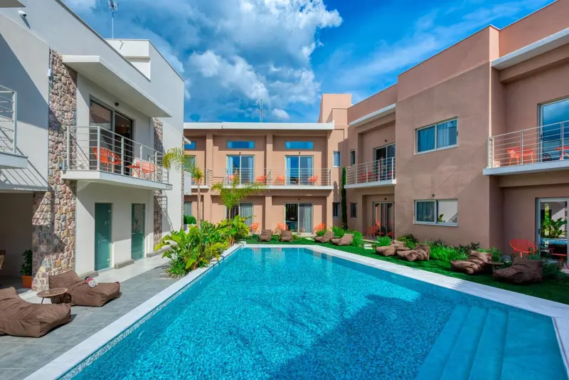 Vue d'une piscine rectangulaire devant un bâtiment à deux étages avec des balcons.