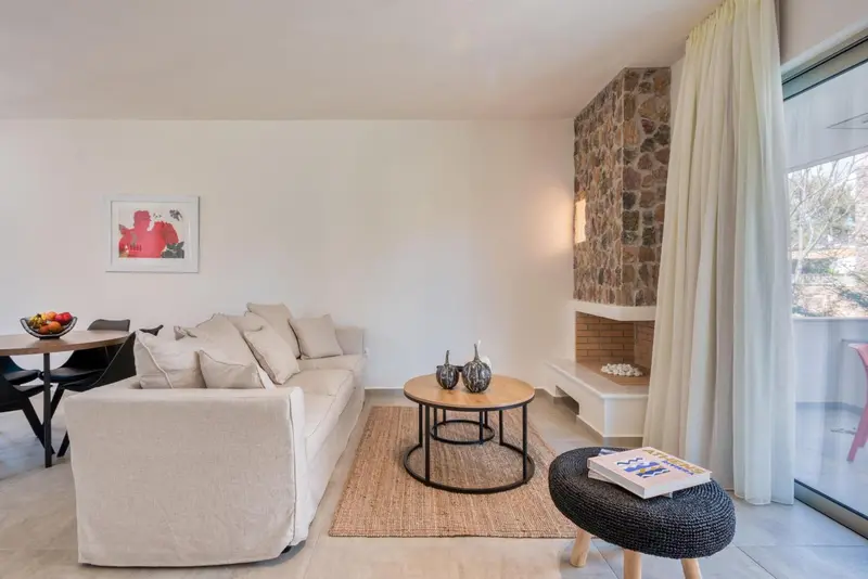 Un salon clair avec un canapé, une table basse et une cheminée en pierre.