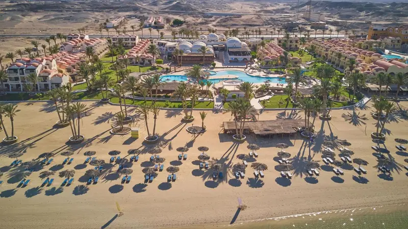 Vue aérienne d'un complexe hôtelier avec piscine et plage de sable.