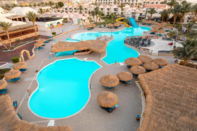 Vue aérienne d'un complexe hôtelier avec plusieurs piscines et des parasols.