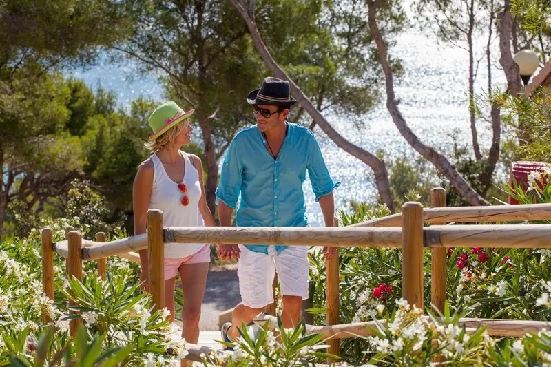 Un couple se promène sur un sentier fleuri en bord de mer.