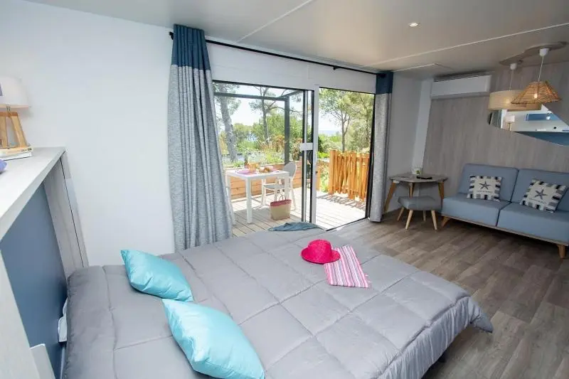 Une chambre lumineuse s'ouvre sur une terrasse en bois.