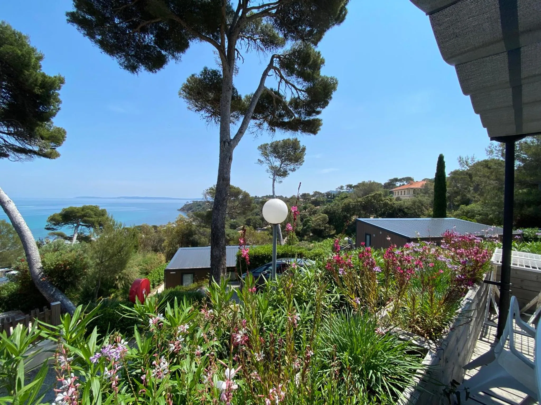 Vue sur la mer et la végétation depuis une terrasse ombragée.