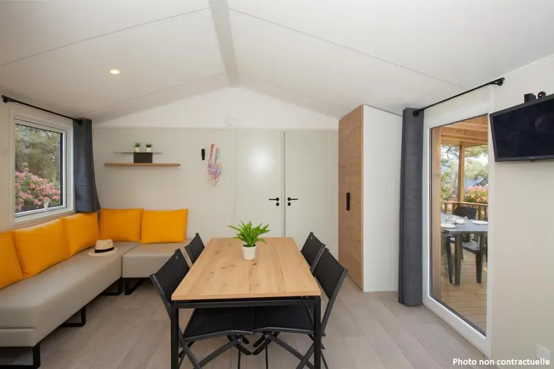 Espace de vie intérieur lumineux avec canapé, table à manger et accès à une terrasse.