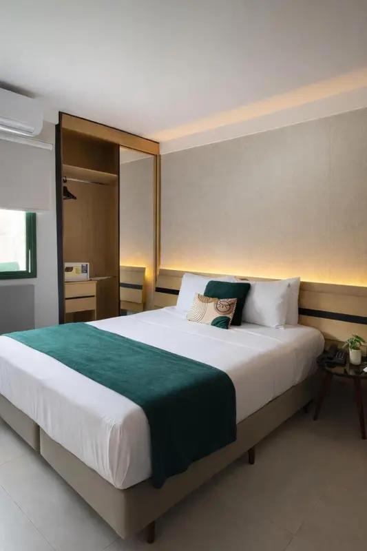 Une chambre lumineuse avec un grand lit recouvert d'une courtepointe verte.
