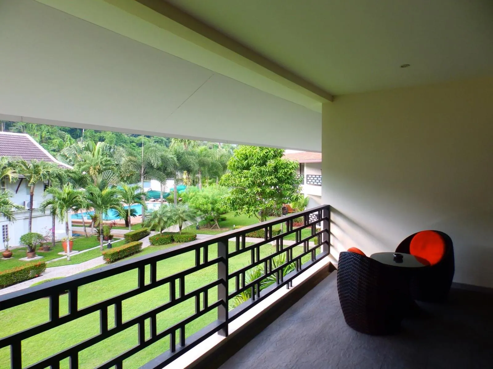Une terrasse avec mobilier d'extérieur offre une vue sur un jardin verdoyant et une piscine.