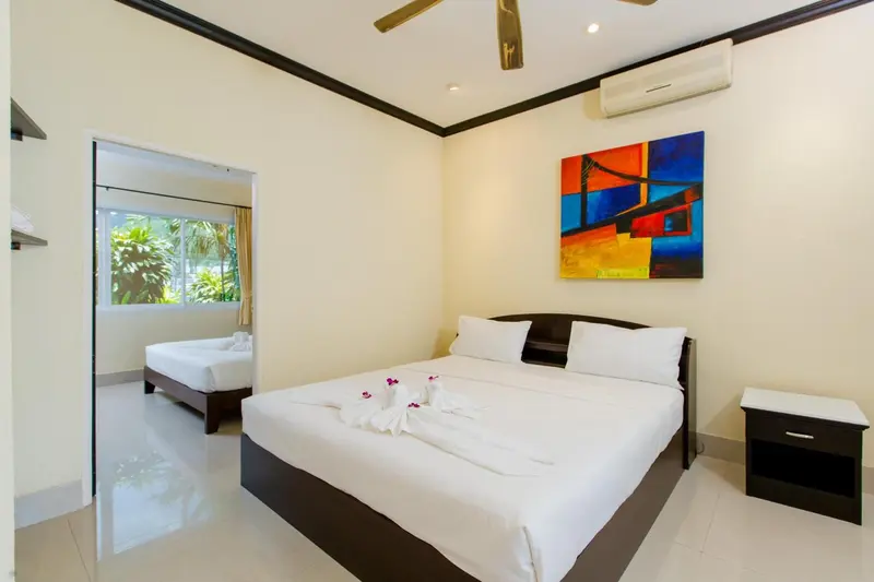 Une chambre lumineuse avec deux lits et une décoration murale colorée.