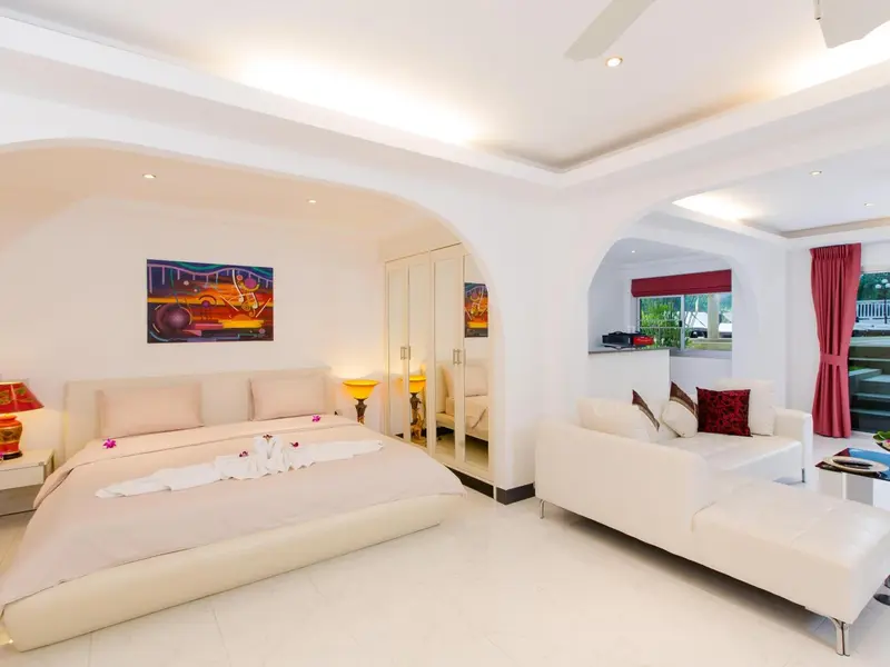Une chambre lumineuse avec un grand lit et un espace salon.