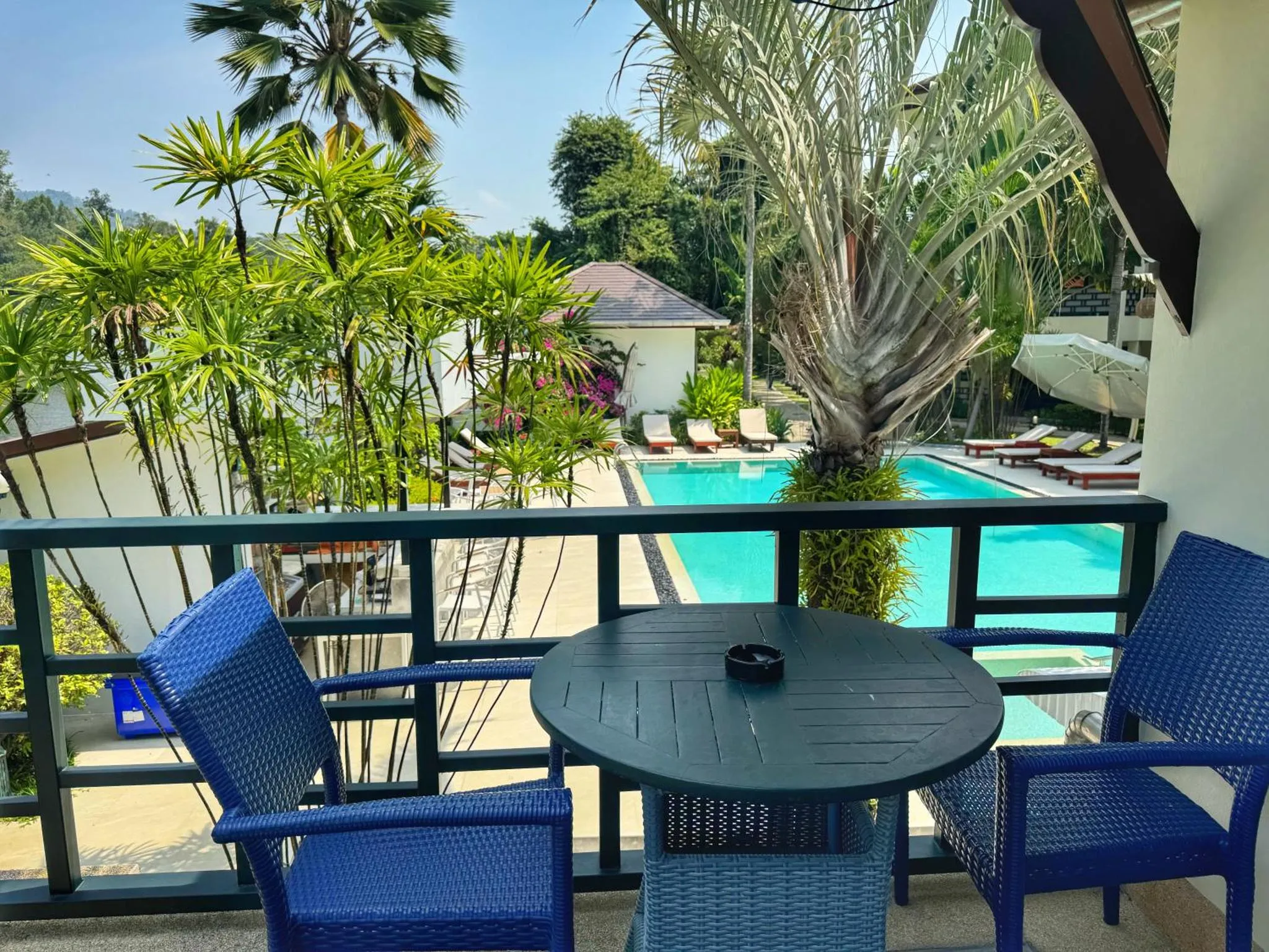 Terrasse avec mobilier de jardin et vue sur une piscine.