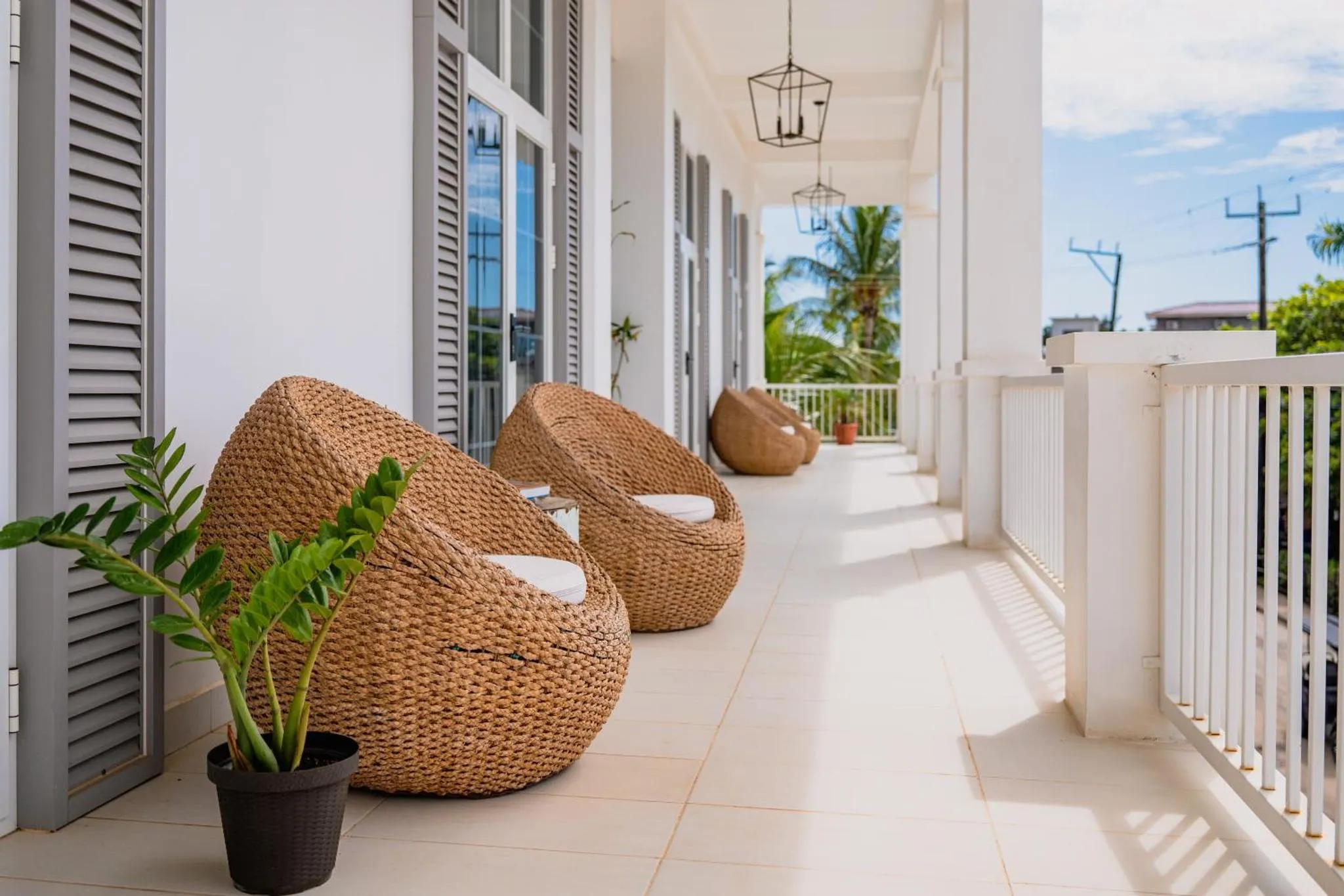 Terrasse avec des fauteuils en rotin et des plantes vertes.