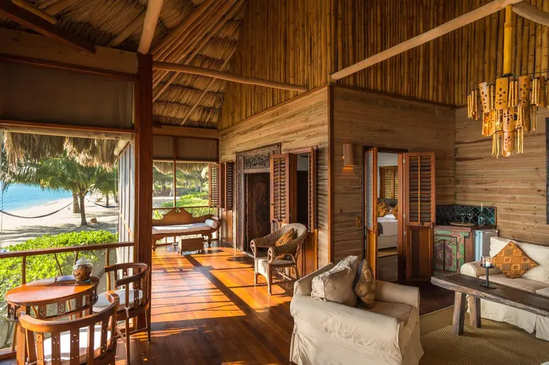 Espace de vie intérieur lumineux avec mobilier en bois et vue sur la plage.