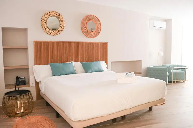 Une chambre lumineuse avec un grand lit et des éléments de décoration en rotin.