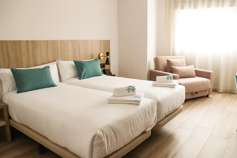 Une chambre lumineuse avec un grand lit et un fauteuil confortable.