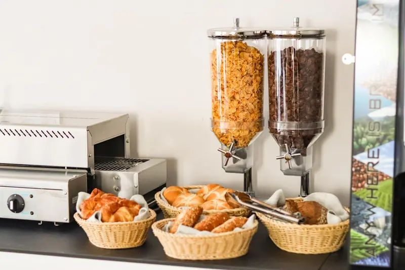 Des viennoiseries et des céréales sont présentées dans des distributeurs et des paniers.