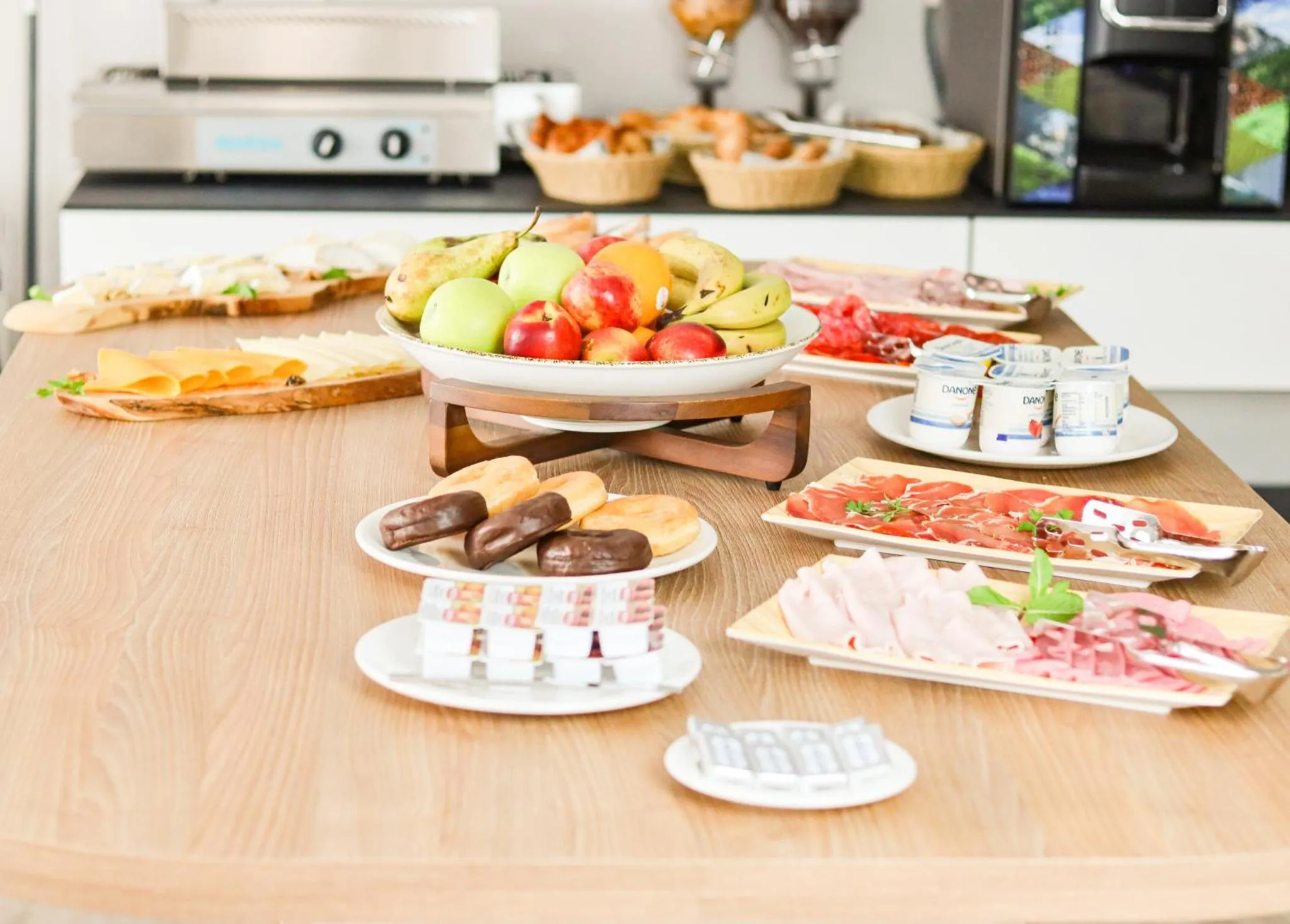 Une table garnie de viennoiseries, de fruits et de charcuteries.