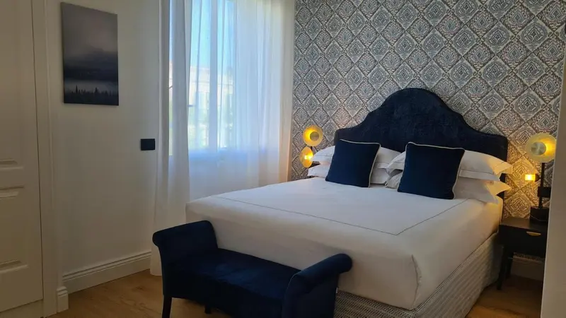 Une chambre à coucher avec un grand lit recouvert de draps blancs et de coussins bleus.