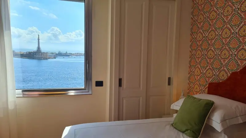 Une chambre lumineuse avec vue sur la mer et un monument.
