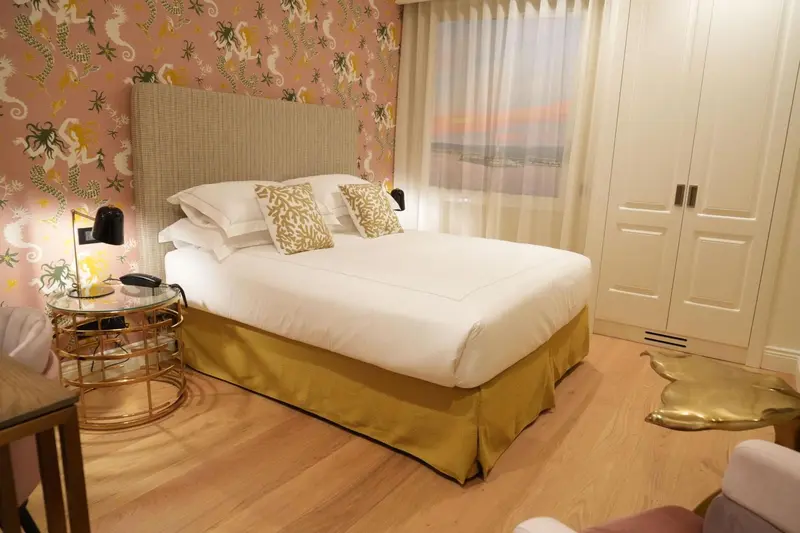 Une chambre lumineuse avec un grand lit et un décor floral.