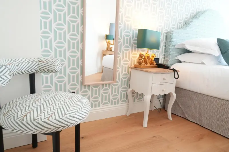 Une chambre lumineuse avec un lit recouvert d'oreillers et d'une couverture blanche.