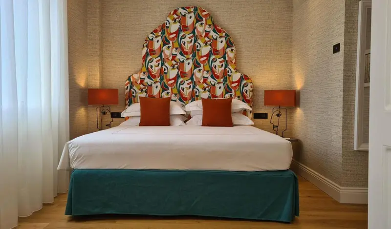 Un lit double avec une tête de lit colorée dans une chambre décorée.