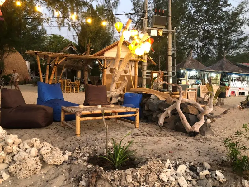 Espace de détente en bord de mer avec mobilier en bois et éclairage festif.