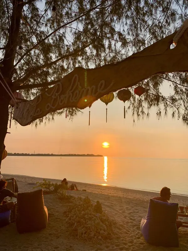 Coucher de soleil sur l'océan avec des personnes assises sur une plage.