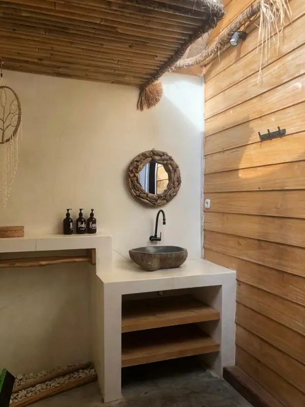 Une salle de bain lumineuse avec un lavabo en pierre et des murs en bois.