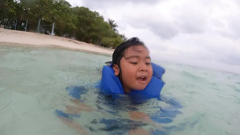 Une personne flotte sur le dos dans une eau turquoise.