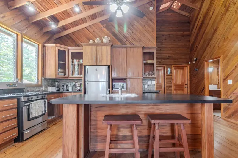 Une cuisine lumineuse en bois avec un îlot central et des tabourets.