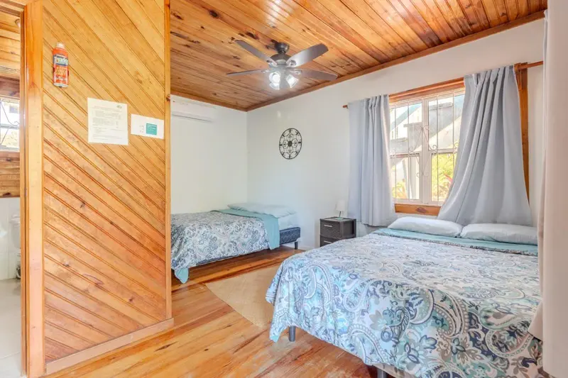 Chambre lumineuse avec deux lits et décoration murale en bois.