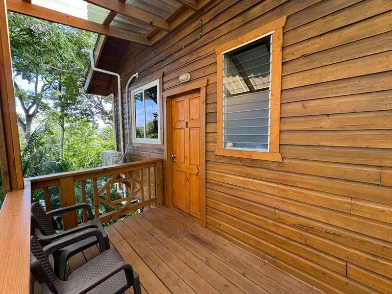 Façade en bois d'un bungalow avec une terrasse et des chaises.