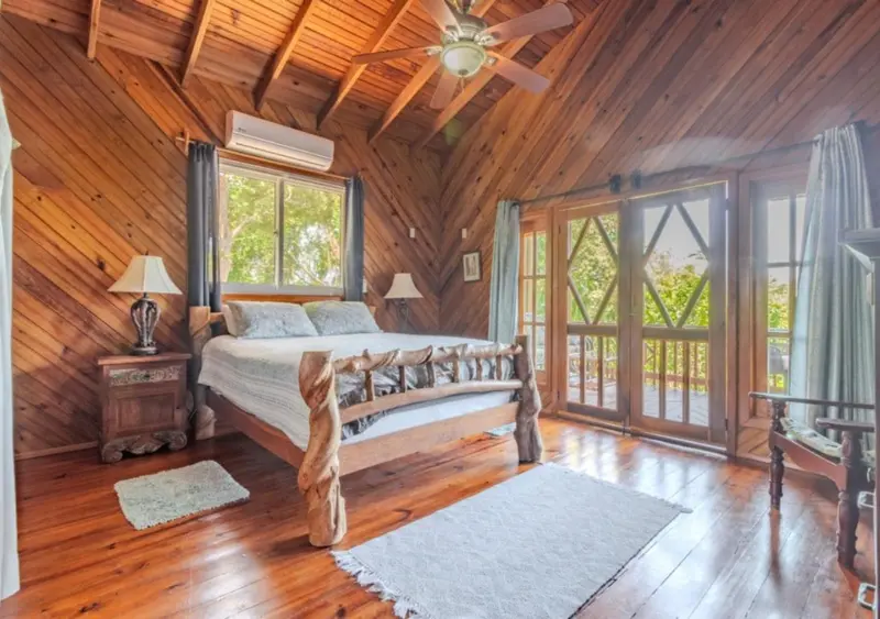 Une chambre lumineuse avec un lit sculpté en bois et un accès à une terrasse.