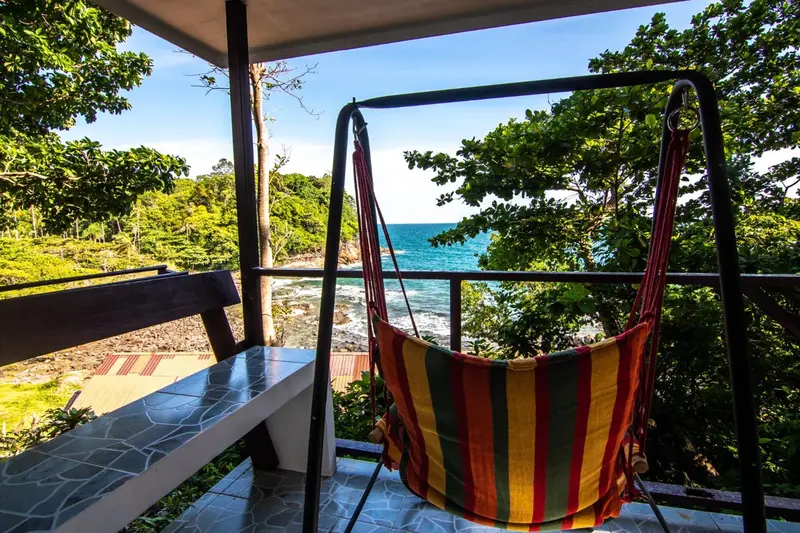 Un hamac coloré suspendu sur une terrasse en bois avec vue sur la mer.