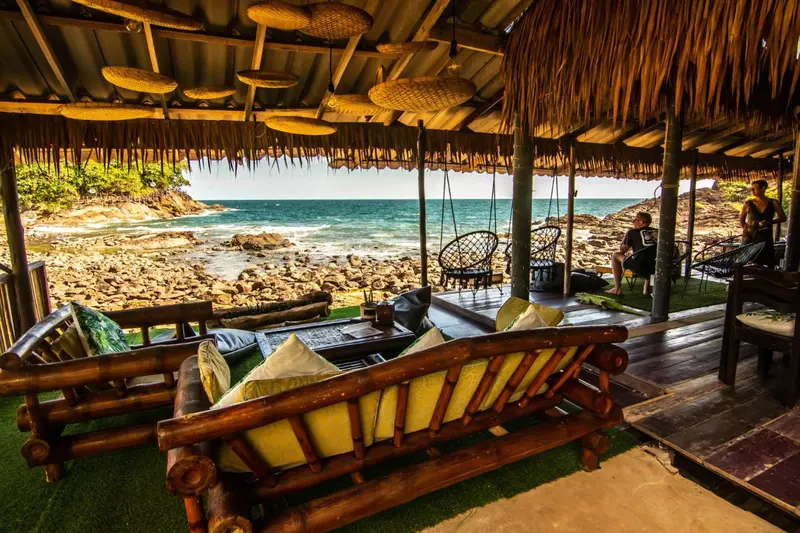 Espace de détente extérieur avec mobilier en bois et vue sur la mer.