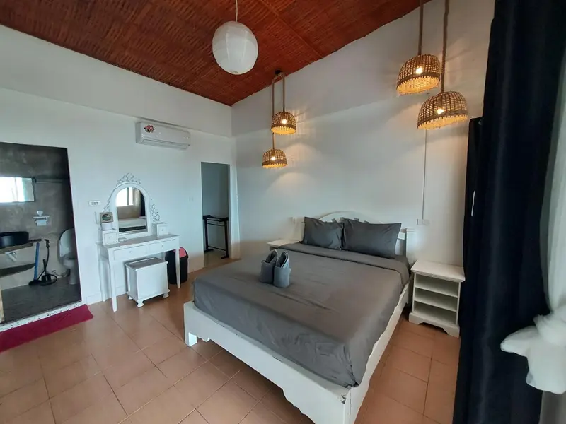Une chambre lumineuse avec un grand lit et un coin coiffeuse.