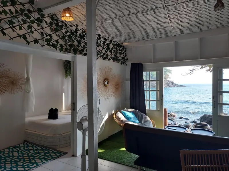 Espace de détente intérieur avec fauteuil suspendu et vue sur la mer.