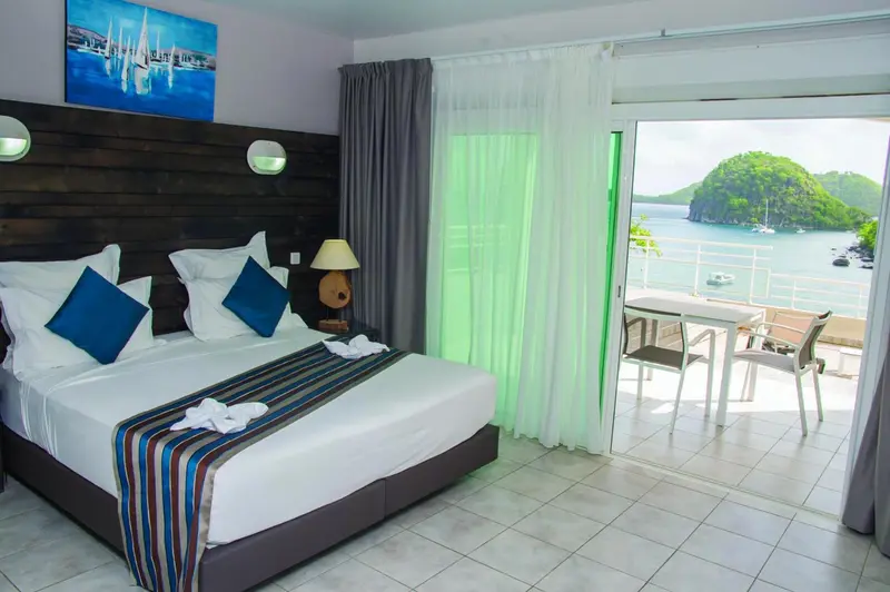 Une chambre lumineuse avec un grand lit et un accès à une terrasse offrant une vue sur la mer.