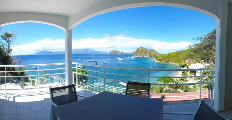 Vue sur une baie ensoleillée depuis une terrasse ombragée.