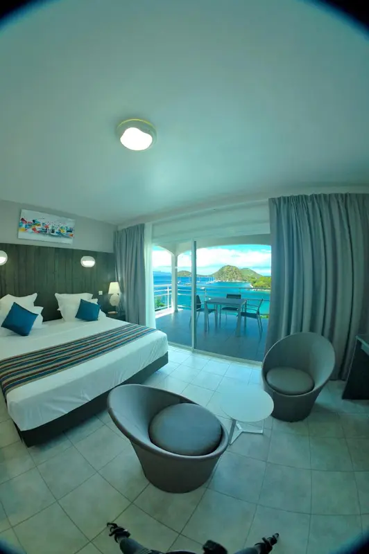 Une chambre lumineuse s'ouvre sur une vue mer depuis une terrasse.